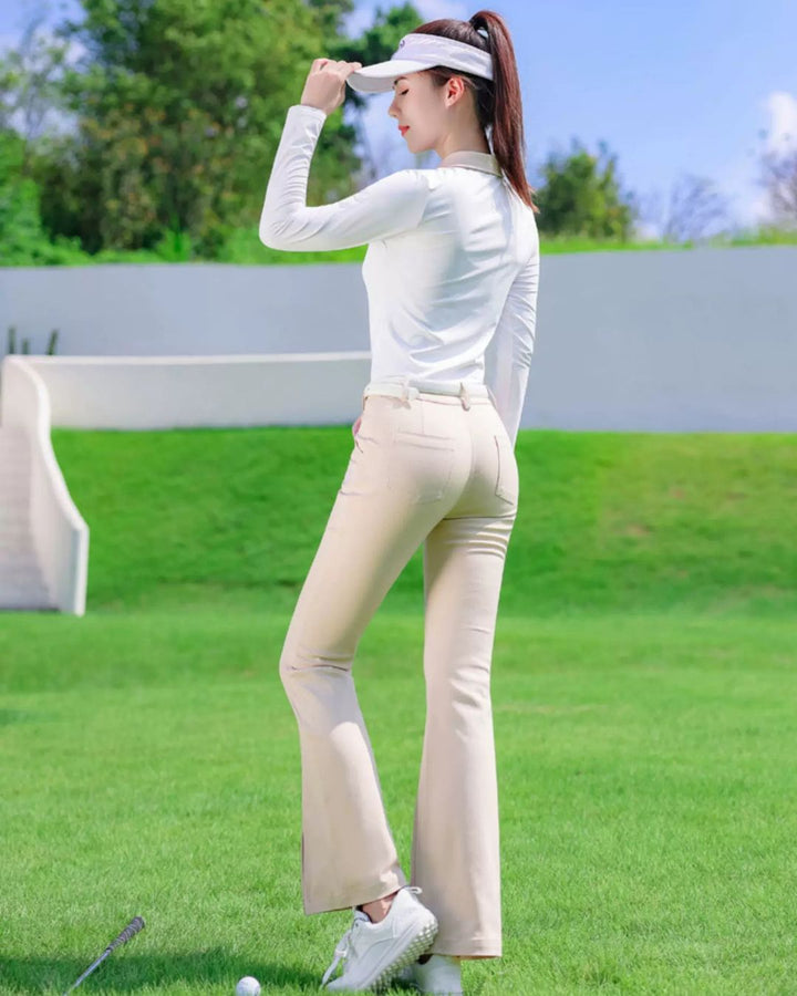 Chamuleのベージュ色フレアゴルフパンツを着用し、ゴルフ場でポーズをとる女性。美脚シルエットのスタイリッシュなデザイン。