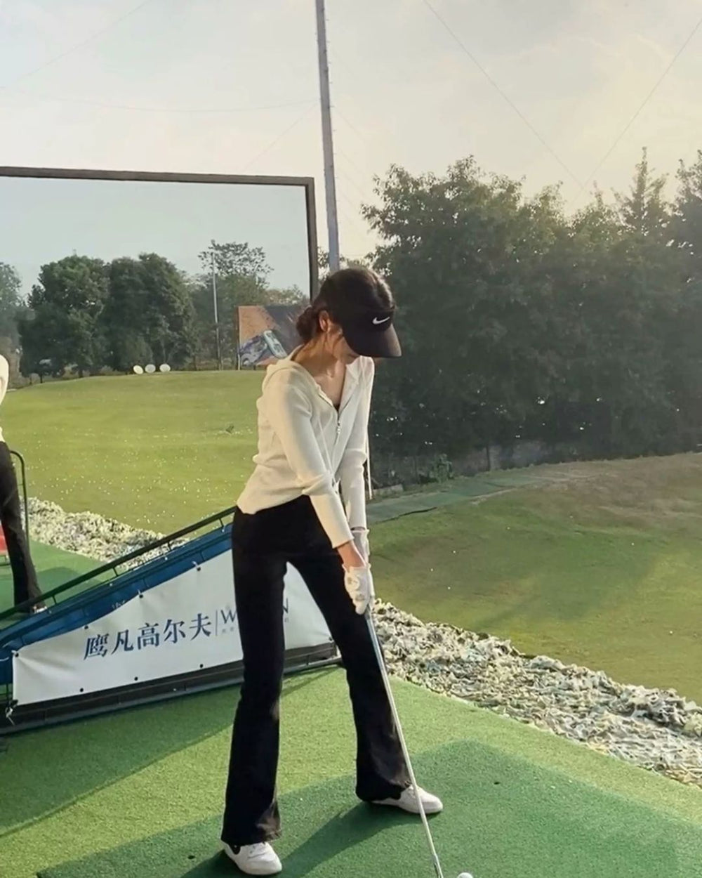 Chamuleの美脚フレアゴルフパンツを着用し、ゴルフ場でスイングの練習をする女性