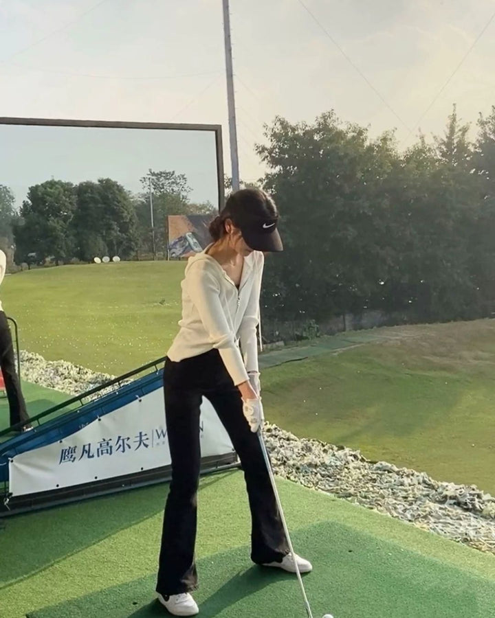 Chamuleの美脚フレアゴルフパンツを着用し、ゴルフ場でスイングの練習をする女性