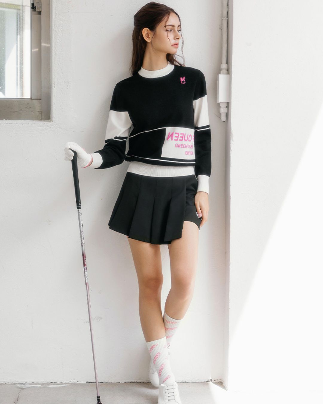 Chamuleのブラックとホワイトのカラーブロックニットトップス。ピンクのロゴがアクセントのスポーティーなゴルフウェア
