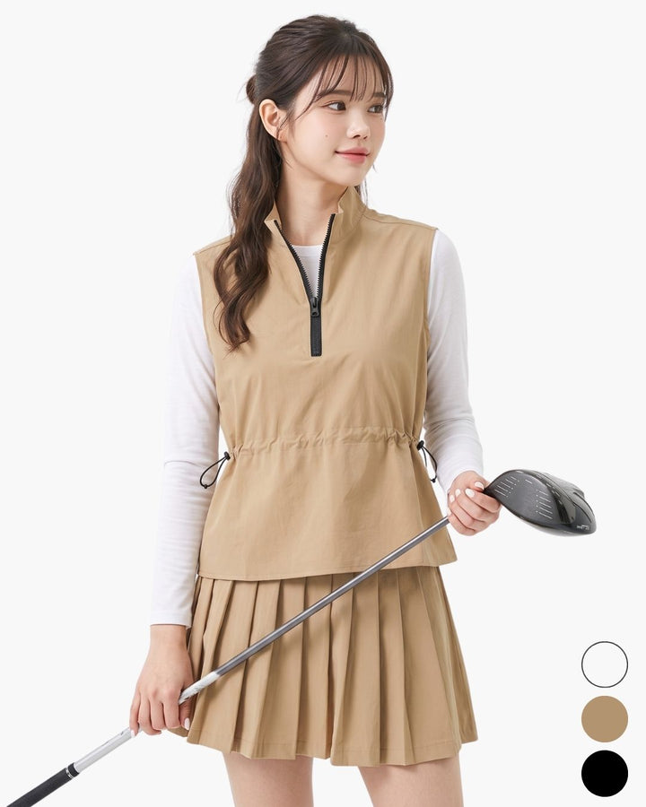 Chamuleのベージュのハーフジップベストとプリーツスカートのセットアップを着用した女性ゴルファー