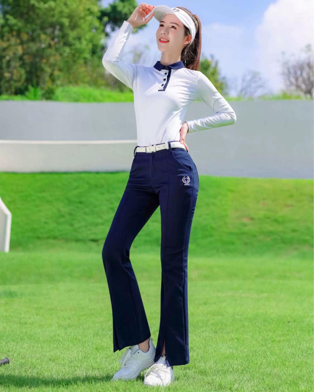 Chamuleの美シルエットフレアゴルフパンツを着用し、ゴルフ場でポーズをとる女性。ネイビーのフレアパンツが脚を長く見せ、スポーティーで上品なスタイルを演出。