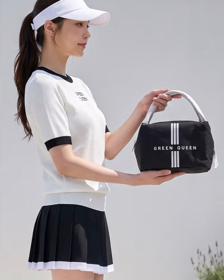 Chamuleのロゴ入りブラック保冷バッグを持つゴルフウェア姿の女性。コンパクトなスクエア型で持ち手付きのポリエステル製。