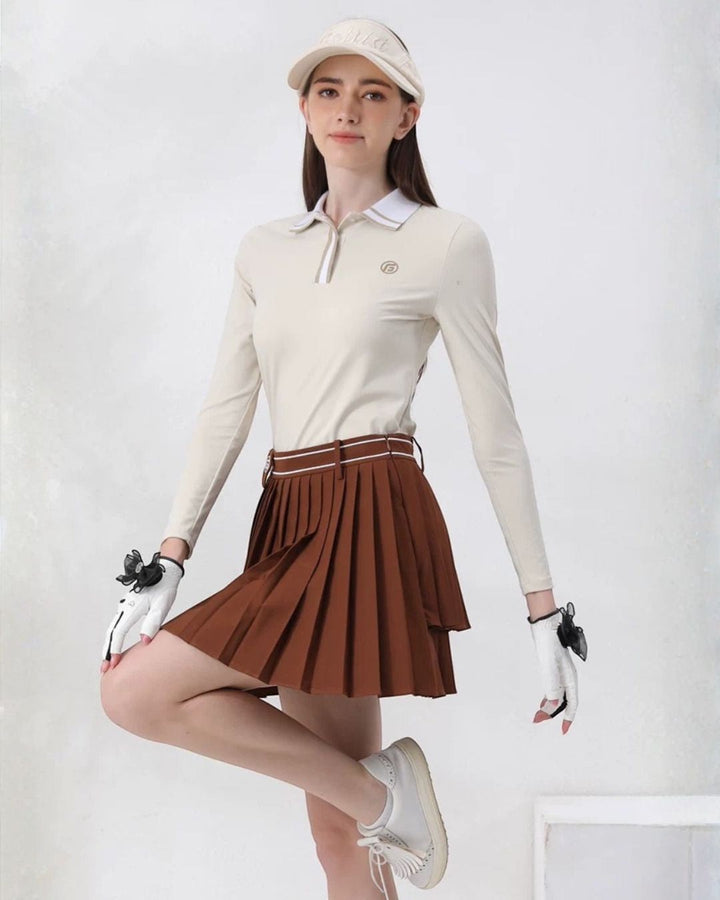 Chamuleのアイボリーの長袖ポロシャツとブラウンのプリーツスカートを着用した女性ゴルファー