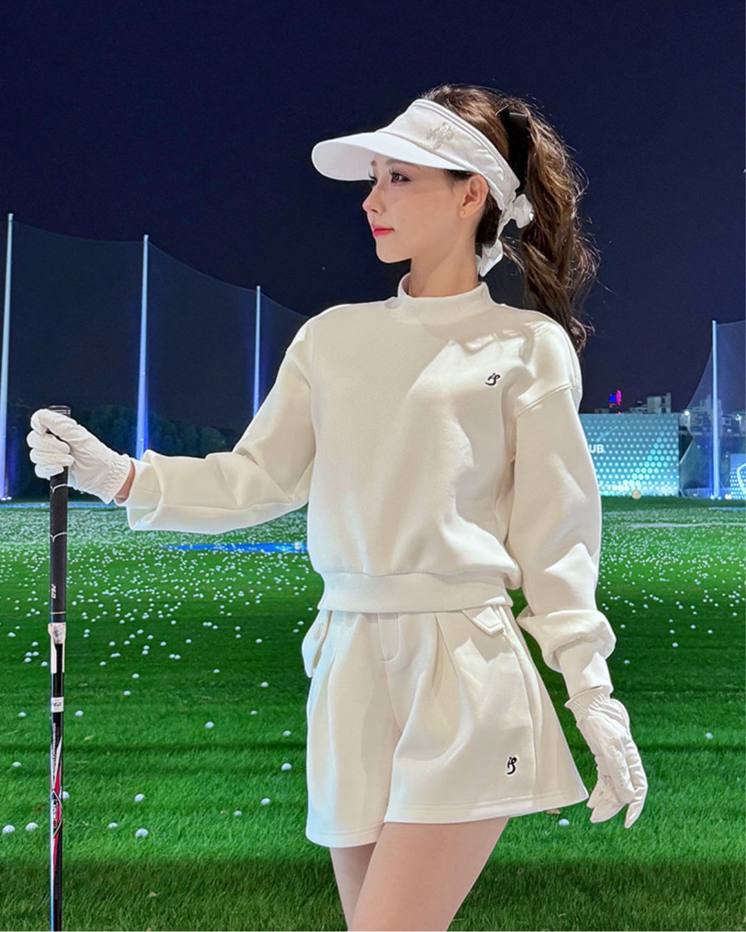 Chamuleのワンポイントゴルフセット。ホワイトのトップスとショートパンツのセットアップを着用した女性ゴルファー。