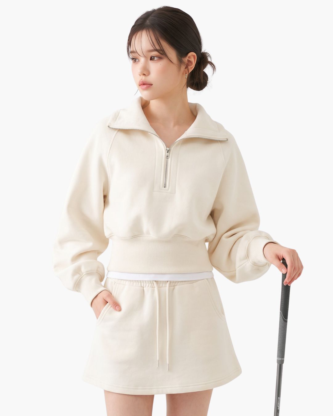 Chamuleのハーフジップフーディとミニスカートのセットアップ。柔らかなアイボリーカラーのスポーティーで女性らしいゴルフウェア。