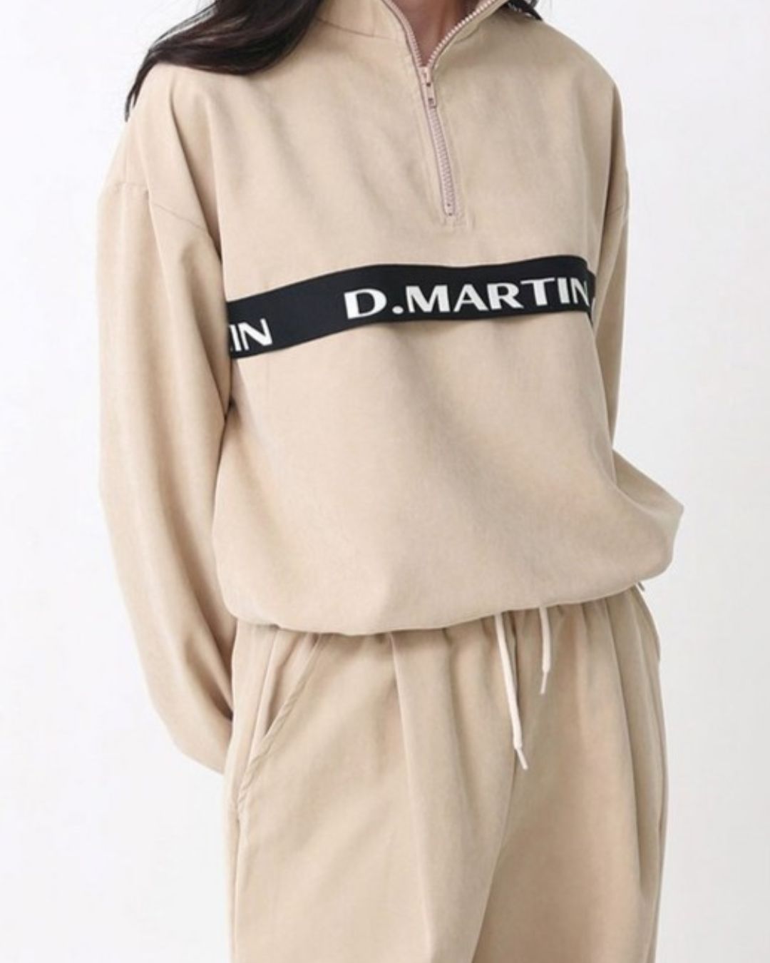 Chamuleのベージュのハーフジップトップス。胸元のロゴラインが特徴で、ゆったりとしたシルエットのスポーティーなゴルフウェア。