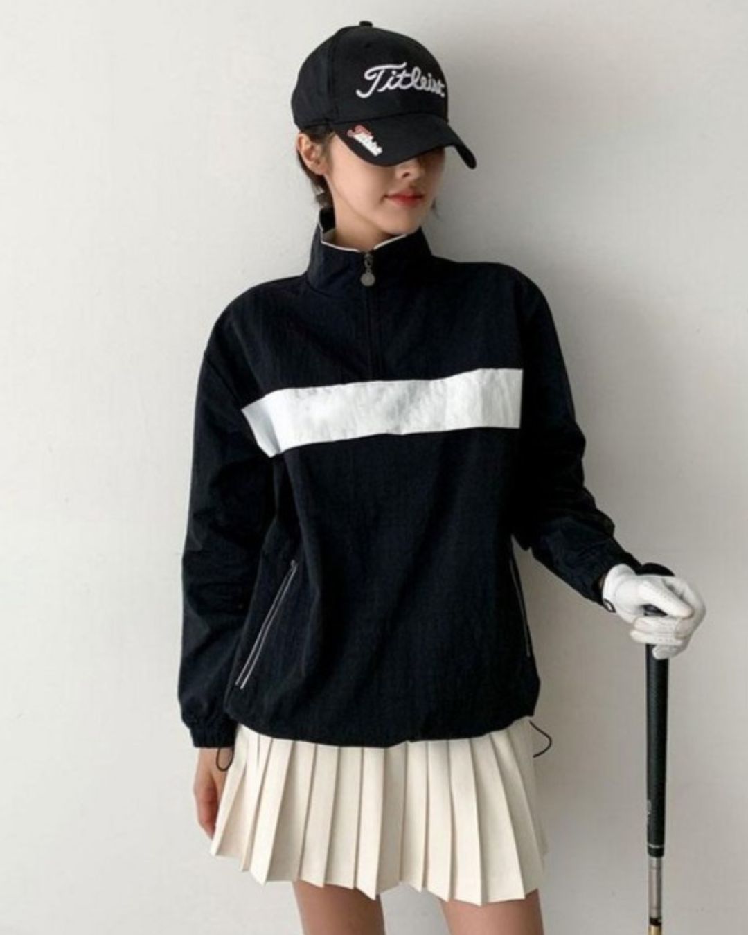 Chamuleの胸元に白いラインが入った黒いハーフジップのスタンドカラースポーツトップスを着用した女性