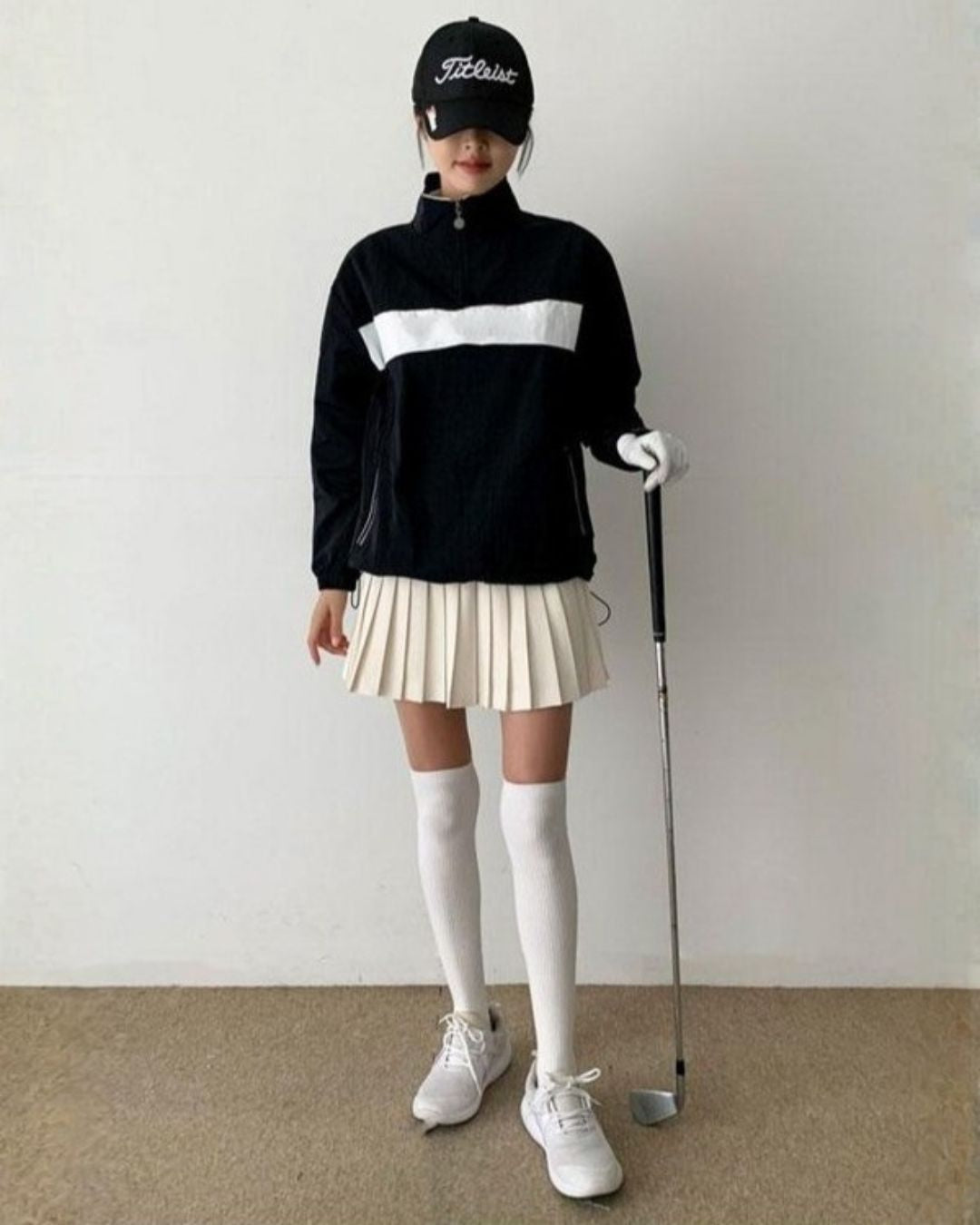 Chamuleの胸元にラインが入ったスポーティーな黒のハーフジップトップス。ゴルフウェアとして着用したコーディネート。