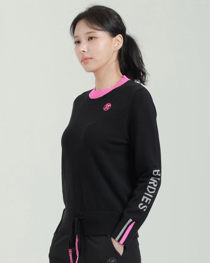 Chamuleのブラックとピンクの配色が特徴的なスポーティーな長袖ロゴニットトップス、ゴルフウェアとして着用
