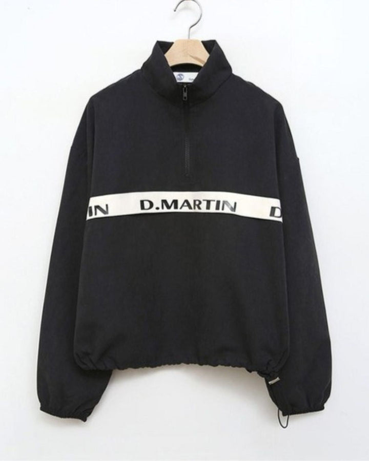 Chamuleのロゴライン入りブラックハーフジップトップス。胸元のロゴと裾のドローコードが特徴のスポーティーなゴルフウェア。