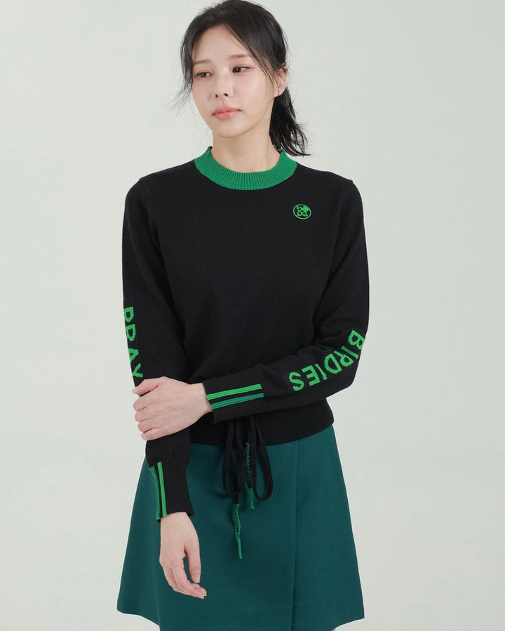 Chamuleのブラックと鮮やかなグリーンのロゴ入り長袖ニットトップスを着用した女性モデル