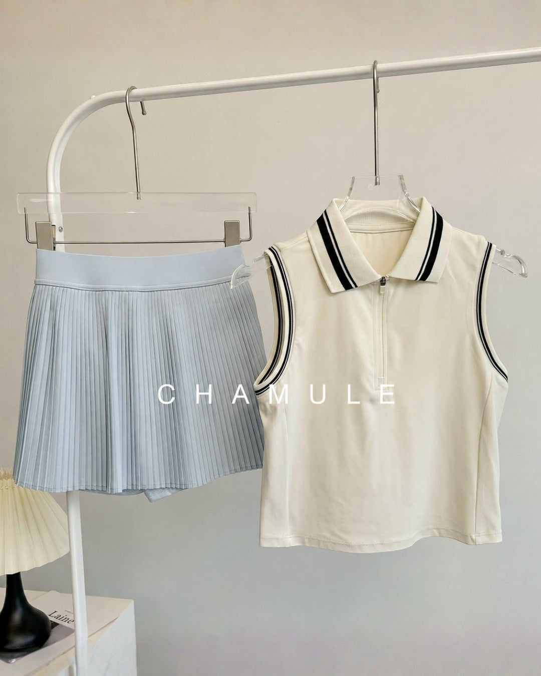 Chamuleのカラフルプリーツセットアップ。襟付きノースリーブトップスとライトブルーのプリーツスカートの組み合わせ。