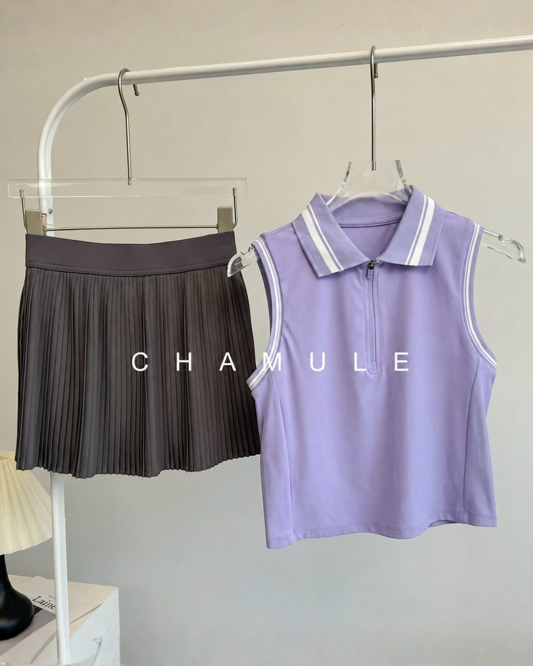 Chamuleのカラフルプリーツセットアップ。ラベンダー色の襟付きノースリーブトップスとダークグレーのプリーツスカート。