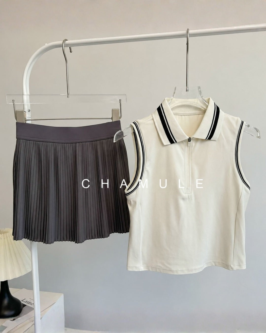 Chamuleのカラフルプリーツセットアップ。ホワイトの襟付きノースリーブトップスとグレーのプリーツスカートの組み合わせ。
