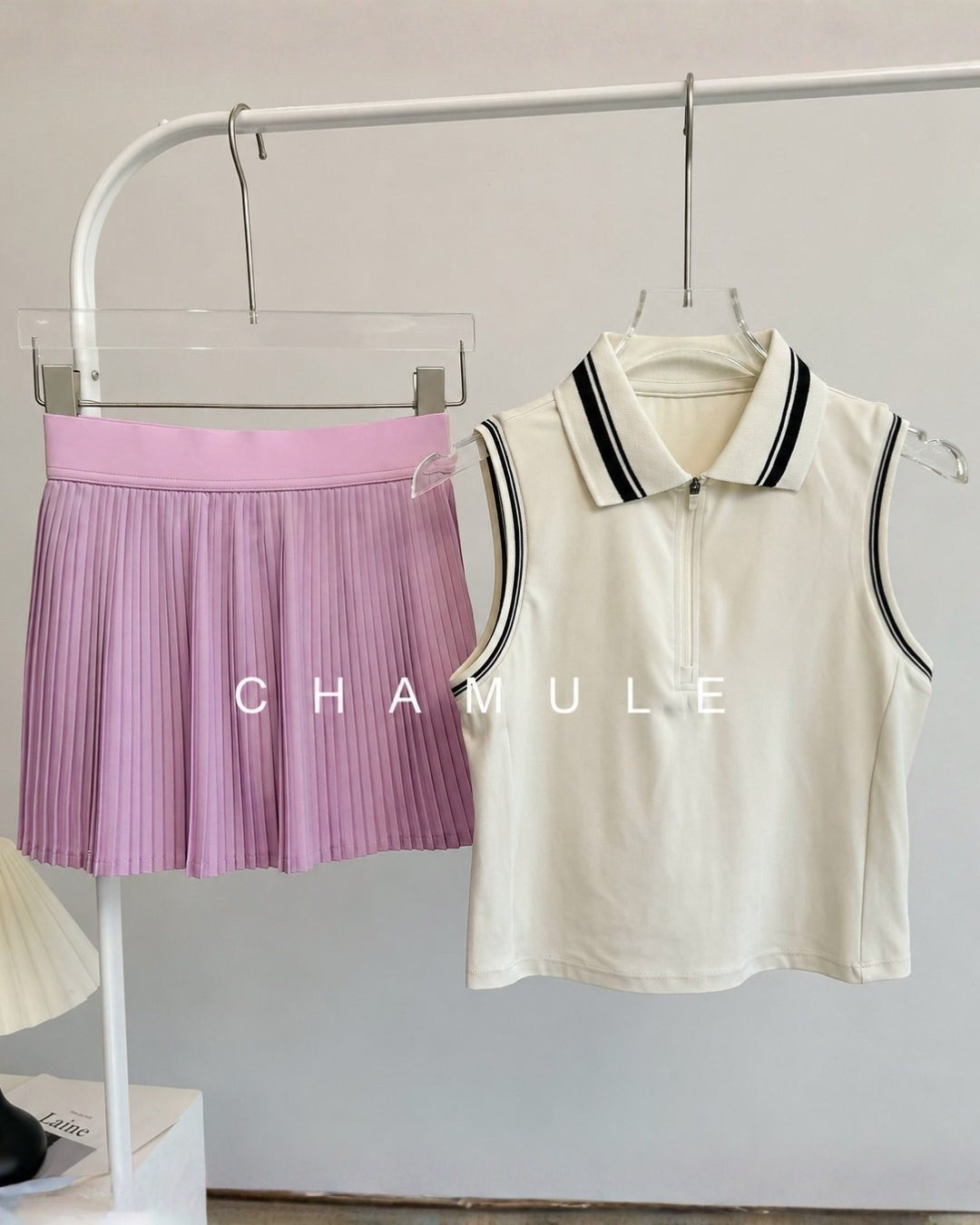 Chamuleのカラフルプリーツセットアップ。ホワイトの襟付きノースリーブトップスと、パープルのプリーツスカートの組み合わせ。