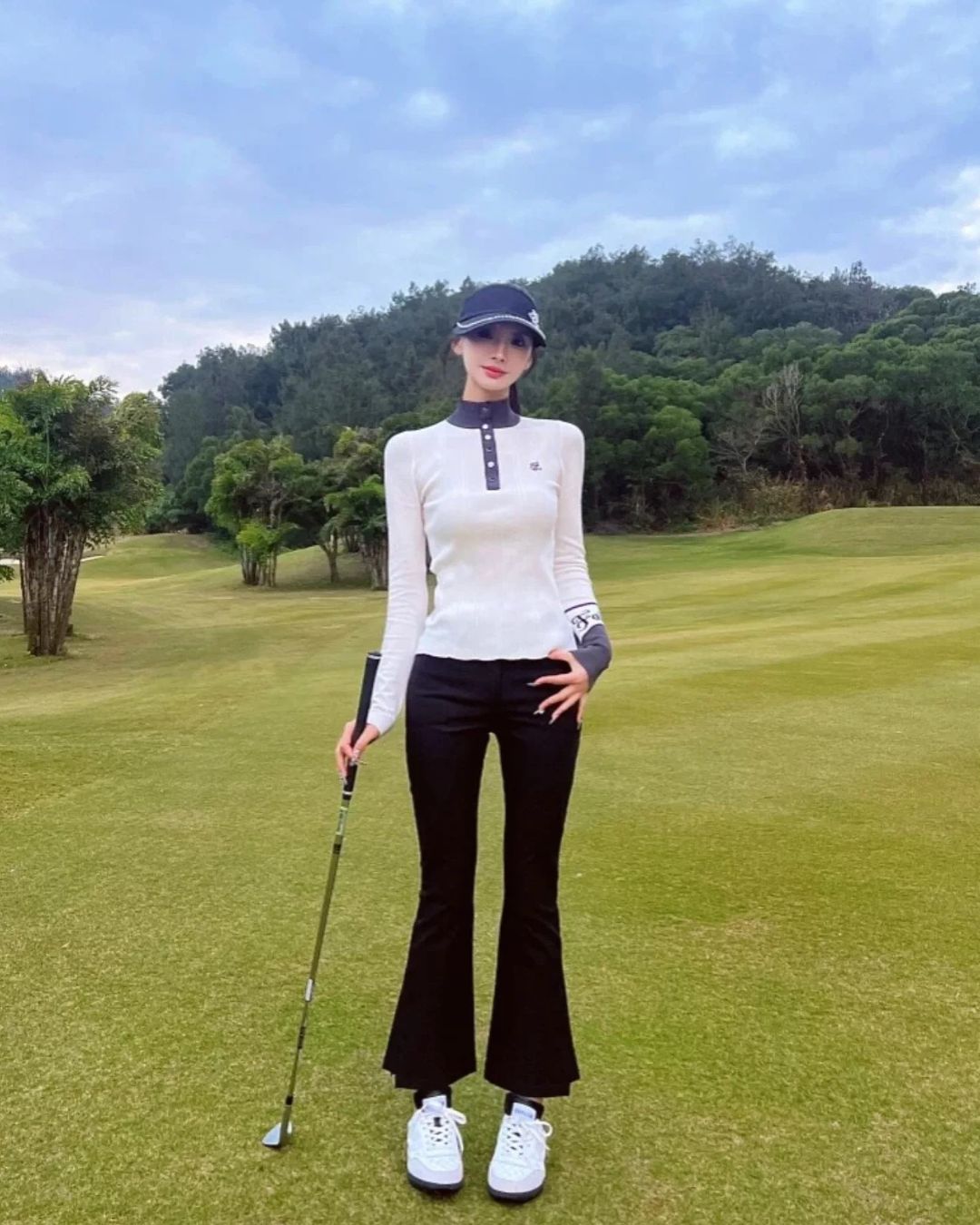 Chamuleの裏起毛スリムフレアゴルフパンツを着用し、ゴルフ場でポーズをとる女性ゴルファー