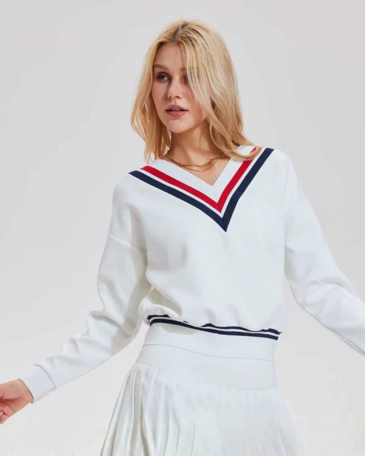 Chamuleのトリコロールライン入りVネック長袖ゴルフトップスを着用したブロンドの女性