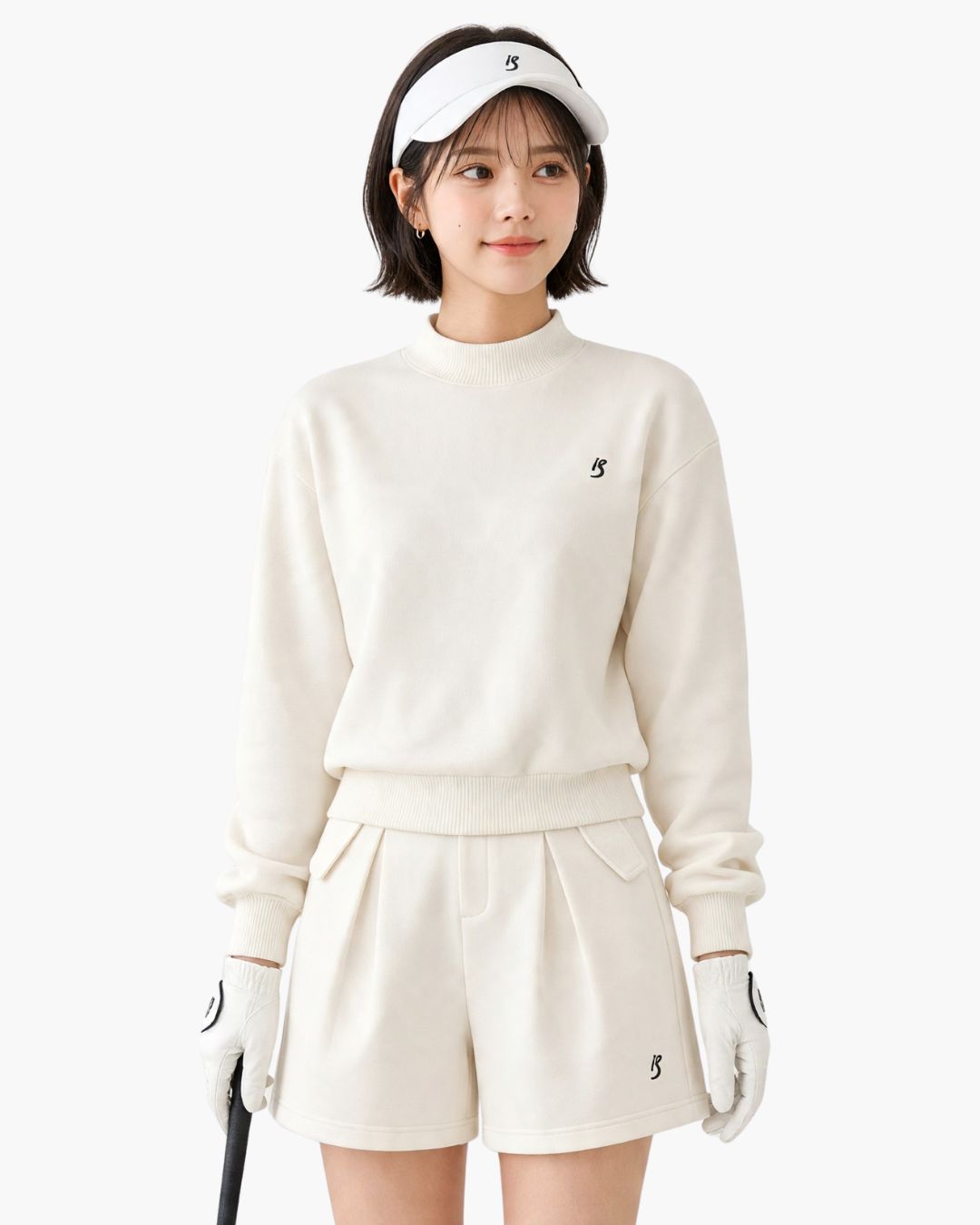 Chamuleのワンポイントロゴ入りホワイトゴルフウェアセットアップ。トップスとショートパンツを着用した女性ゴルファー