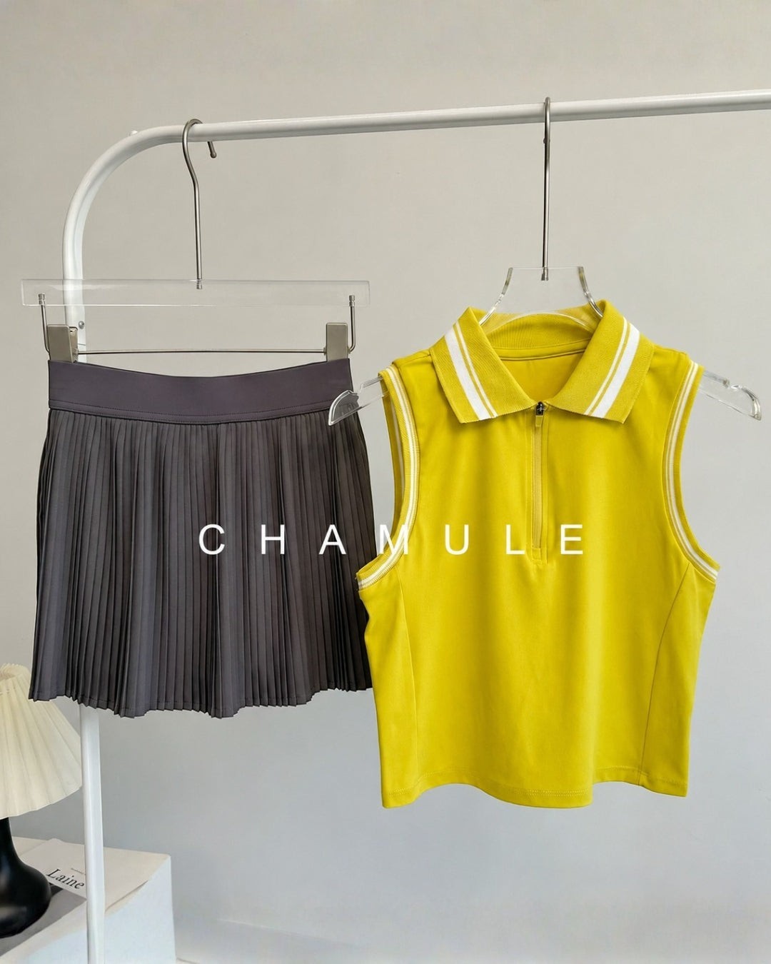 Chamuleのカラフルなノースリーブトップスとグレーのプリーツスカートのセットアップ。襟付きでスポーティーなデザイン。